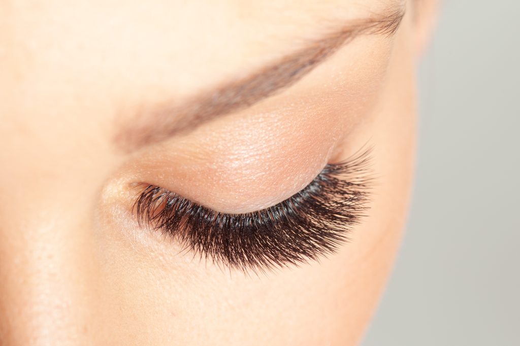 Close-up of a closed eye with long, defined lashes and a shaped brow