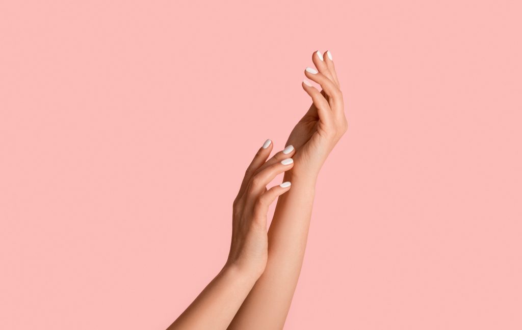 Hands raised against a soft pink background